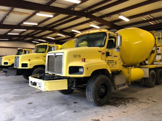 Yellow Mack mixer trucks under the SuperMixers shed